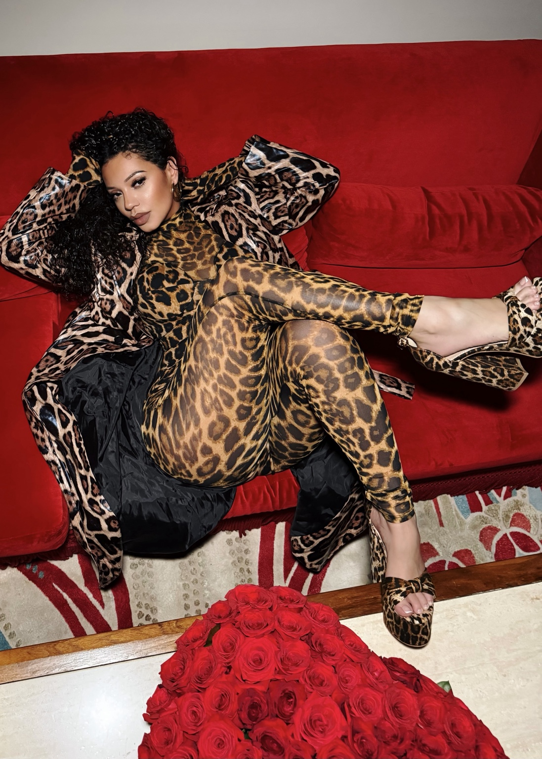 Natalie in a leopard editorial look on a red sofa