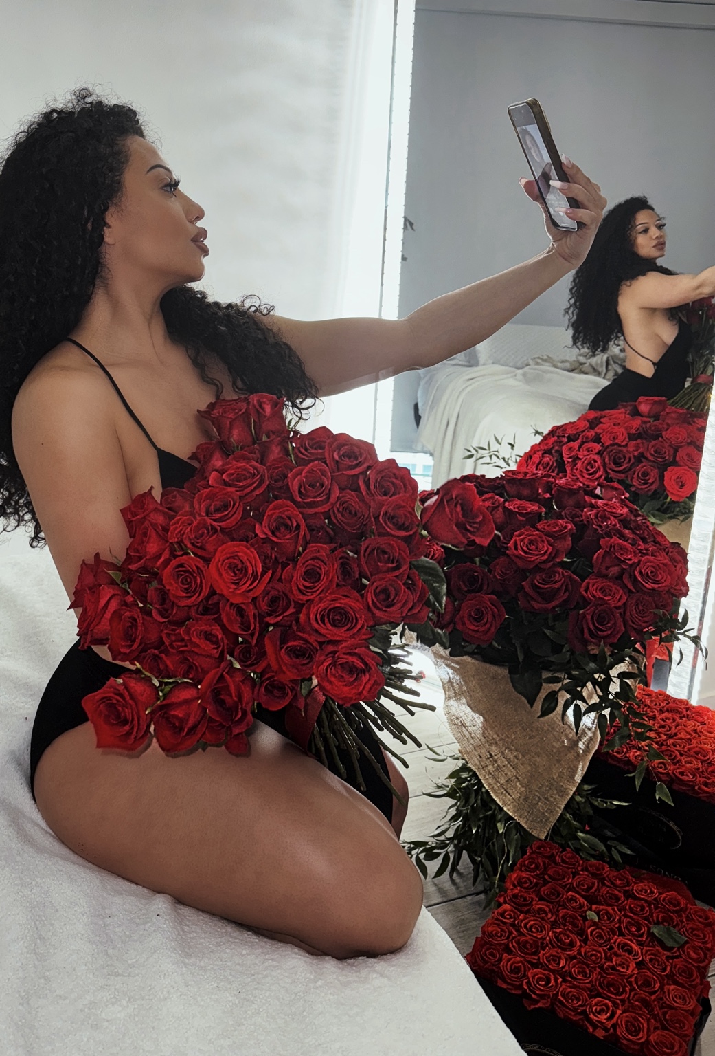 Natalie holding her phone beside red roses